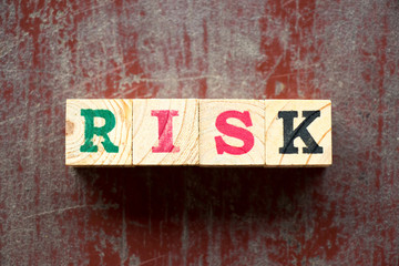 Letter block in word risk on old red wood background