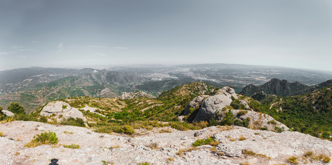 Fototapeta na wymiar Panoramic views of the valley from the mountains of Montserrat. Near Barcelona, Spain. Beautiful nature in shades of green on a background of blue sky