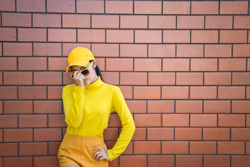 Portrait asian hipster girl on brick wall background,she wear yellow tone full body,Lifestyle of thailand people
