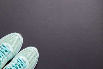 Turquoise sneakers and turquoise dumbbells with a white sole on a black background