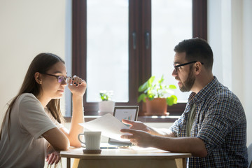Concerned millennial business workers discussing contract, confused man expressing his thoughts, female listening attentively. Employees negotiating over deal or agreement. Concept of work dispute