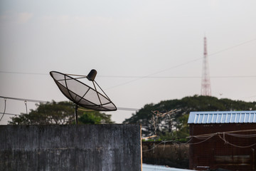 Satellite dish and TV antennas on the house roof with blue sky background