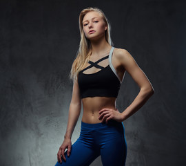Fototapeta na wymiar Sexy slim blonde girl in a sportswear posing in a studio.