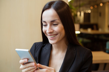 Gorgeous smiling woman texting on the phone indoors