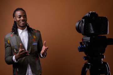 Young handsome African businessman against brown background