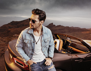 Portrait of a hansome man relaxing next to the car