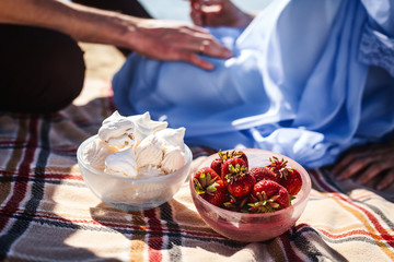 young couple eating strawberry and marshmallow. resting on beach, handsome man and cute woman on coast river, happy family concept