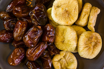 dried dates and figs in a ceramic plate on a wooden table