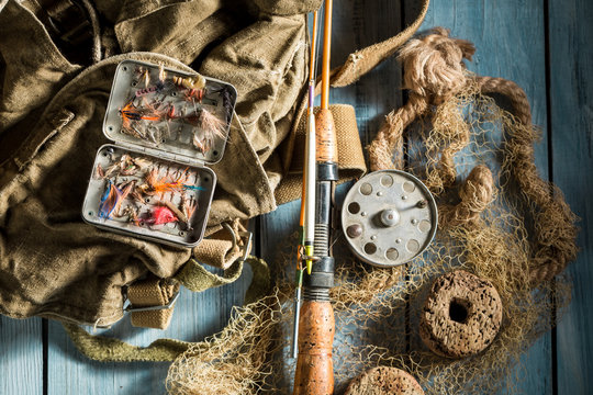 Fishing tackle with fishing flies and rods on wooden table