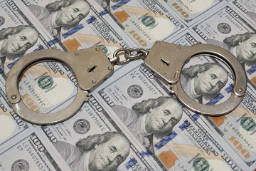 Police handcuffs against a hundred dollar bills USA. Concept violation of the law, corruption,...