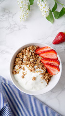 Perfect breakfast: crunchy granola with yoghurt and strawberries with a cup of black coffee on marble table