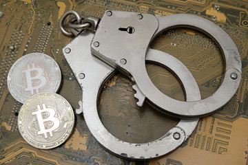 The concept of a violation of the law, cybercrime, financial fraud. Two coins of bitcoin and...