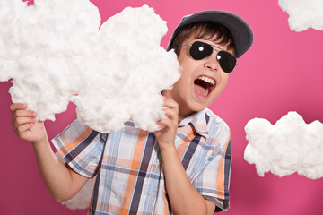 fashionable boy posing on a pink background with clouds