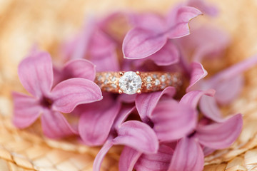 Obraz na płótnie Canvas jewelry engagement ring with diamonds and spring lilac flowers