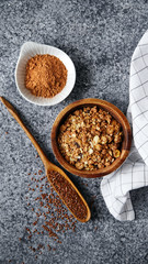 Healthy sweets cooking ingredients: granola, sesame and flax seeds, cocoa in separate bowls on gray background. Flatlay with copy space