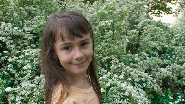 Portrait of a happy child in flowers. A little girl in white flowers.