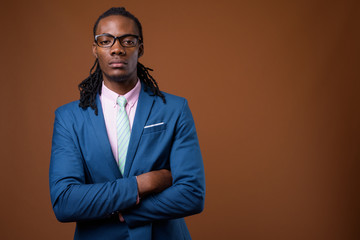 Young handsome African businessman wearing eyeglasses against br