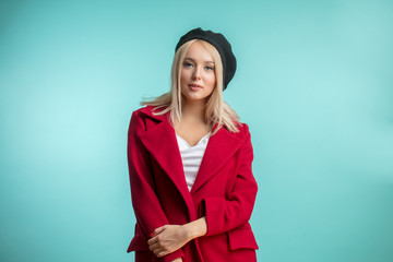 closeup photo of beautiful model in black beret and red overcoat isolated on the blue background. beauty concept