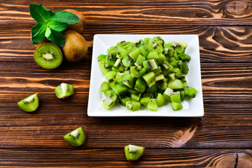 Freshly sliced kiwi fruit with whole kiwis in background.