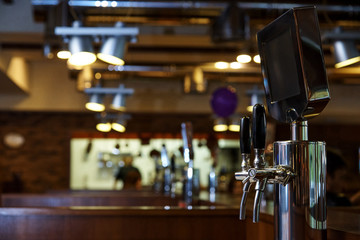 The system of bottling beer on the table of customers on a blurred background of the bar in the brewery.
