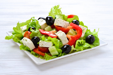 Greek salad on a white wooden background. Space for text or design.