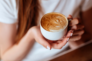 capuccino in hands of young girl