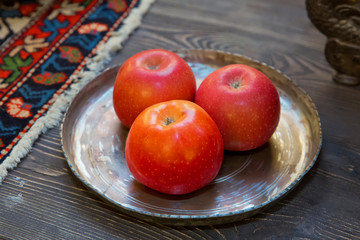 Three red apples are in a copper container