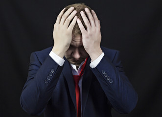 Businessman holding hands behind his head, black background