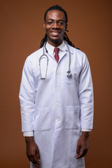 Young handsome African man doctor against brown background