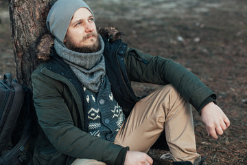 Pensive hipster guy wanderlust with touristic backpack enjoy tranquility during exploring nature environment,