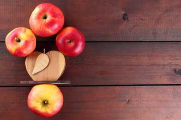 Fruits of oranges and red apples on a dark brown wooden background, halves of oranges on wooden boards. Copy space. Citrus fruits and apples for vegetarian breakfast
