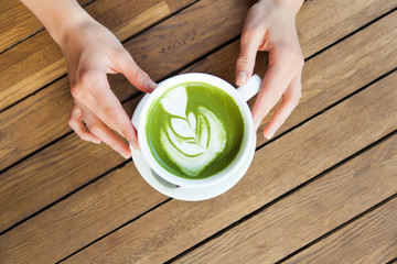 Woman's hands holding cup of tea matcha