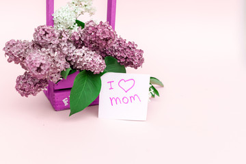 Beautiful bouquet of purple lilac and card on purple paper background