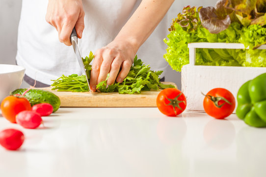 Woman cooking healthy food, cut green vegetable salad. Healthy lifestyle concept.