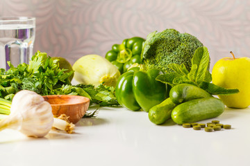 Green vegetables on table. Vegetable vegan diet food background: zucchini, peppers, broccoli, cucumbers, avocado, apple, herbs. Healthy lifestyle concept.