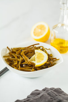 Sea kale kelp salad with oil and lemon in a white plate, white background.