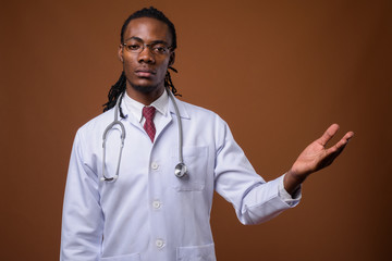 Young handsome African man doctor against brown background