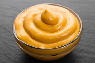 mustard in a bowl on a rustic background