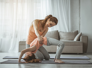 You can do it. Charming woman is holding her child bending over in backwards position. Lady is...