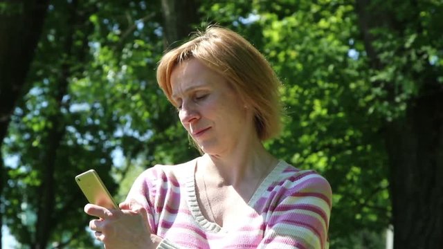 Woman busy using smartphone on nature background.
