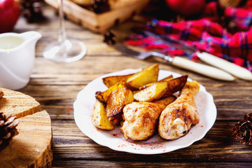 a tasty dish for the holiday, a new year or Christmas, baked potatoes with chicken legs, spices, paprika, sesame, bagel, olive oil, red wine on a wooden background