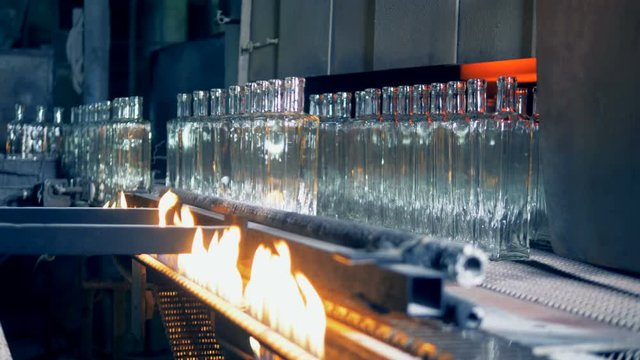 Glass bottles are being relocated from the conveyor belt after getting burned