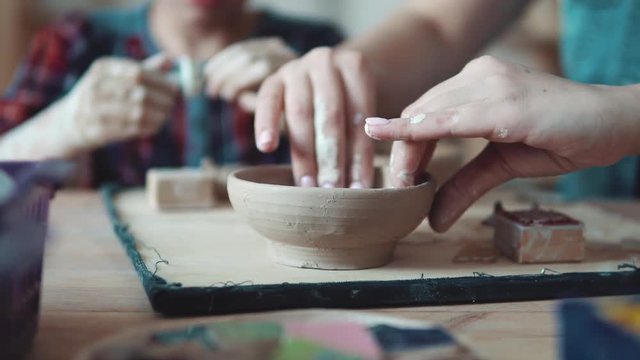 occupation on manual modeling of clay. female hands close-up. girl sculpts a clay plate