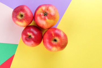 Fruits of oranges and red apples on a multicolored background, halves of oranges and apples on colored paper. Copy space. Citrus in the style of pop art