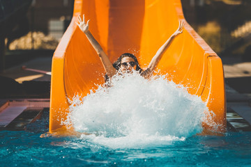 joyful woman going down on the rubber ring by the orange slide make the water splashing in the aqua...