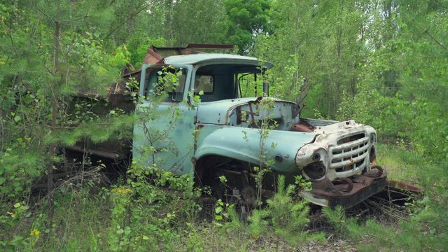 Rusty truck wrecks in the forest in Pripyat. Chernobyl nuclear disaster. Slider shot - Juni 2017: 30km Chernobyl, exclusion zone