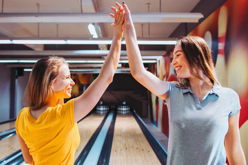 Two women celebrating bowling strike with high five