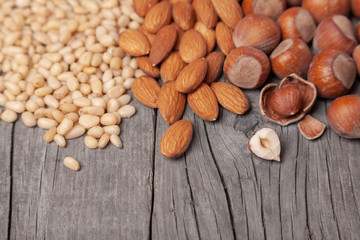 Cedar nuts, almonds and hazelnuts are scattered on wooden table