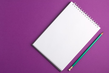 Blank notebook with pencil on purple background. Flat lay concept