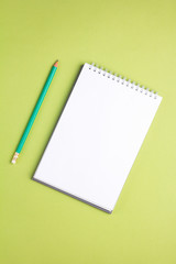 Fototapeta na wymiar Blank notebook with pencil on green pastel background. Flat lay concept. Vertical orientation